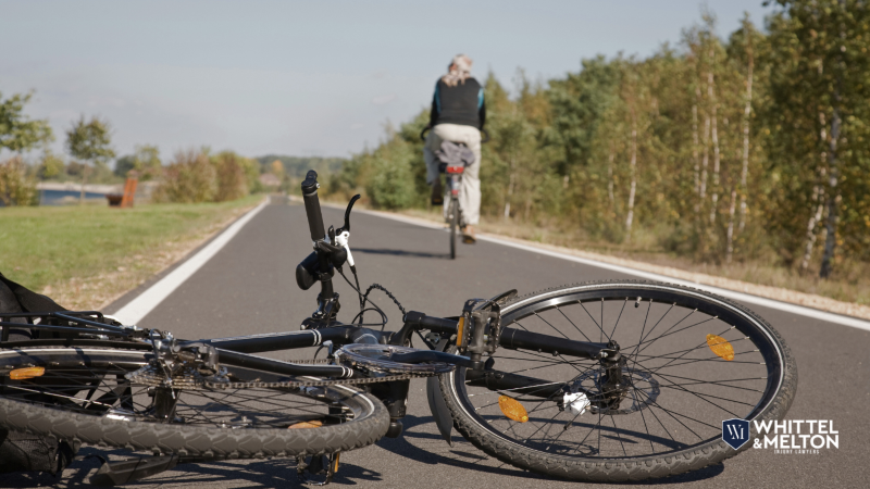 Bicycle Accident Scene on a Path with Whittel & Melton Injury Lawyers Logo