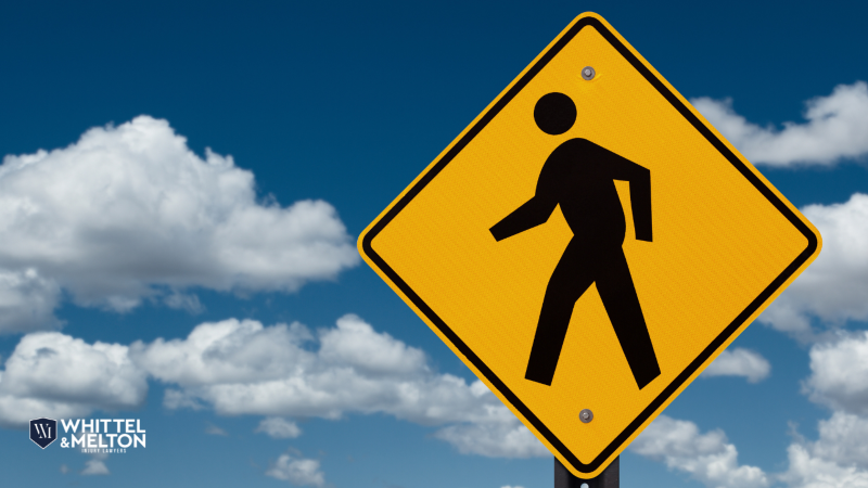 Pedestrian crossing sign against a blue sky with clouds.