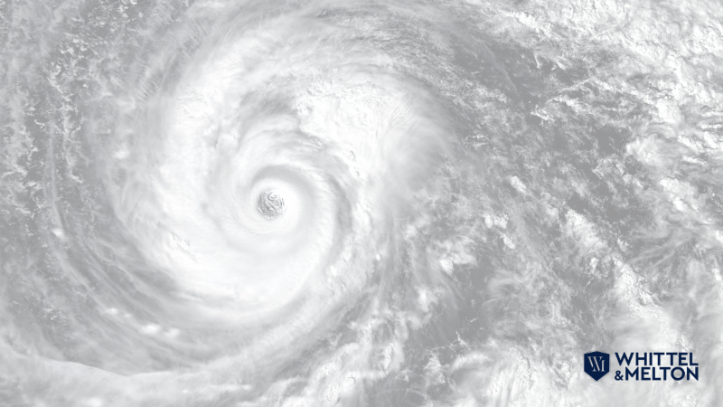 Satellite image of a hurricane with a swirling eye in the center, representing the destructive power of storms. Whittel & Melton law firm logo in the bottom right.