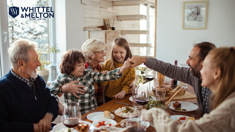 A family enjoying a holiday meal together at a decorated table, smiling and bonding, with Whittel & Melton Injury Lawyers logo in the corner.